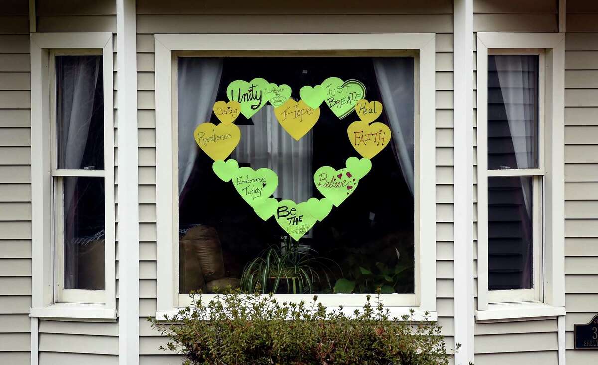 Inspirational messages on hearts are displayed on the front window of a home in Shelton on April 3, 2020.