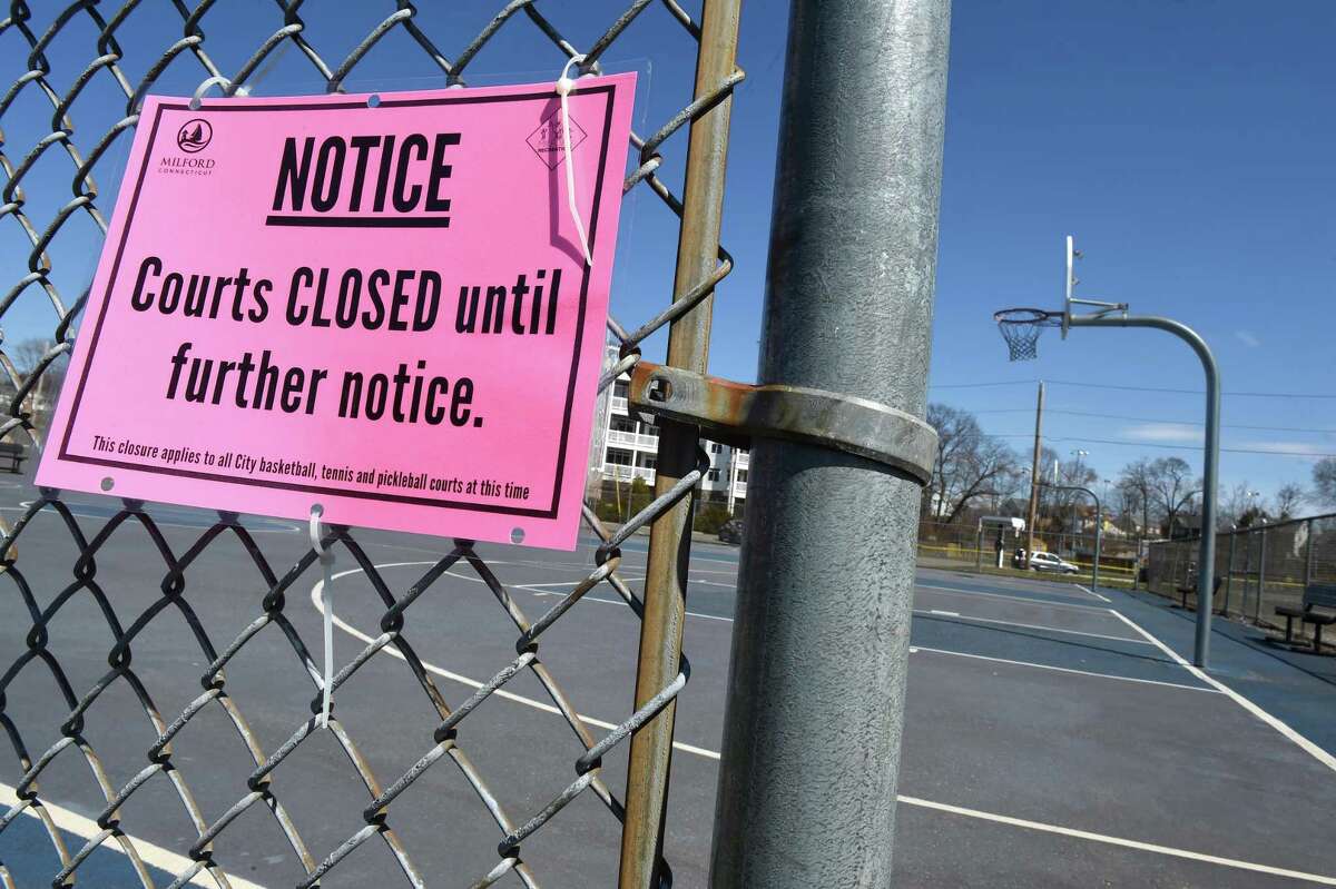 A notice that courts are closed until further notice hangs outside of the basketball courts behind the Milford Public Library on March 27, 2020.