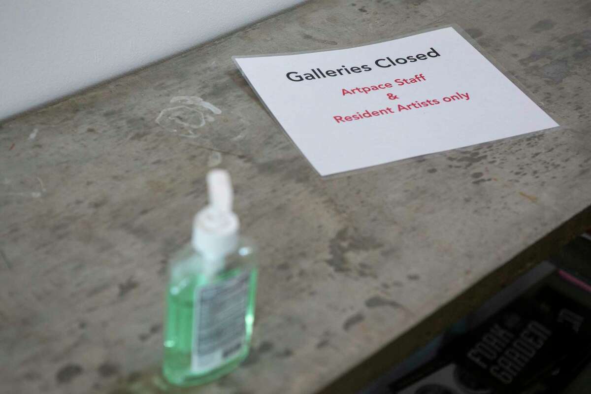 A bottle of hand sanitizer sits next to a sign announcing the closure of galleries inside Artpace.