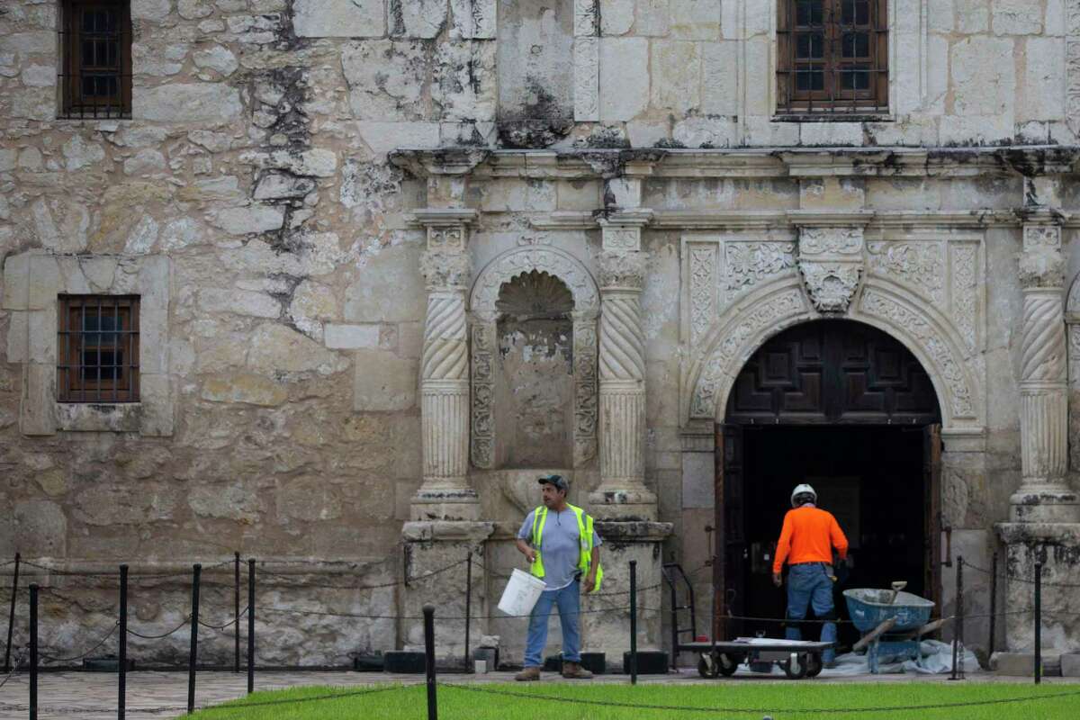 Workers move materials outside the Alamo in downtown San Antonio on Thursday. There are few tourists in the area; the Alamo, many hotels, restaurants, stores and attractions are closed because of restrictions to slow the spread of the deadly novel coronavirus. But repair work on the historic mission fort and on the first phase of the $450 million makeover of Alamo Plaza is continuing. Construction is exempt from the orders outling the restrictions.