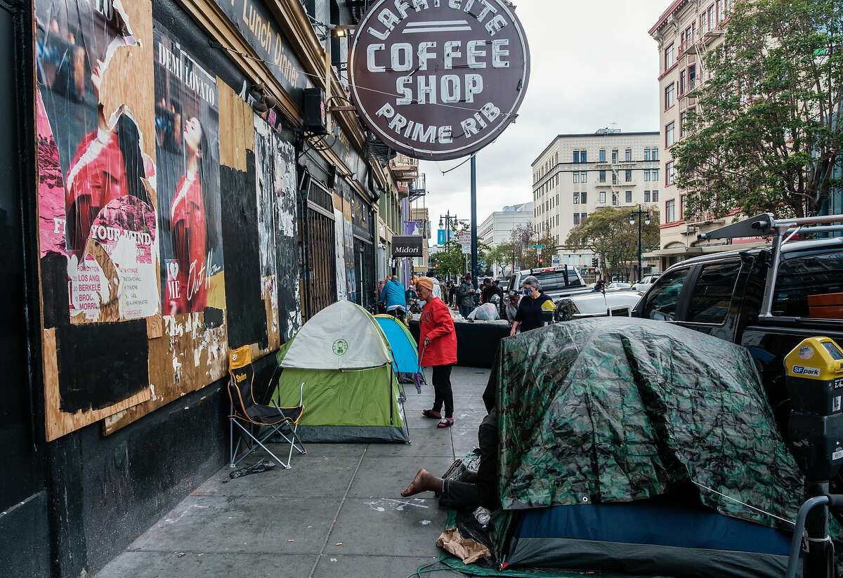 People are seen near a row of tents in the Tenderloin in San Francisco, Calif. on Friday April 10, 2020.