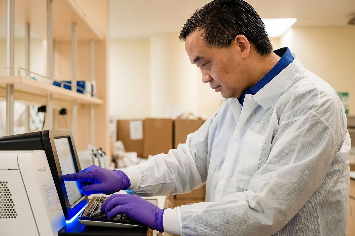 Microbiologist Dr. Charles Chui checks on the newly installed NextSeq 550 which will sequence COVID-19 genomes in San Francisco, Calif. on Friday, March 20, 2020. The infectious disease specialist at UCSF is sequencing the genomes of every case of COVID-19 in the Bay Area that he can get his hands on.