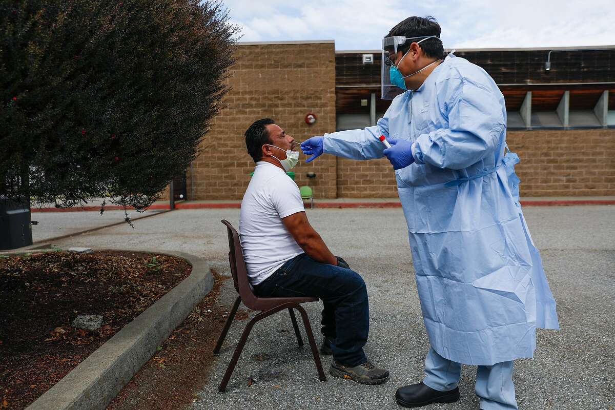 Dentist Dr. Marco Reyes (right) tests patient Jose Maldonado (left) for Covid-19 in San Francisco, California on Thursday, April 9, 2020. A small tent in the Southeast Health Center parking lot was serving as an alternative testing site for potential COVID-19 cases. Patients who are tested have been pre-screened by a health care provider.