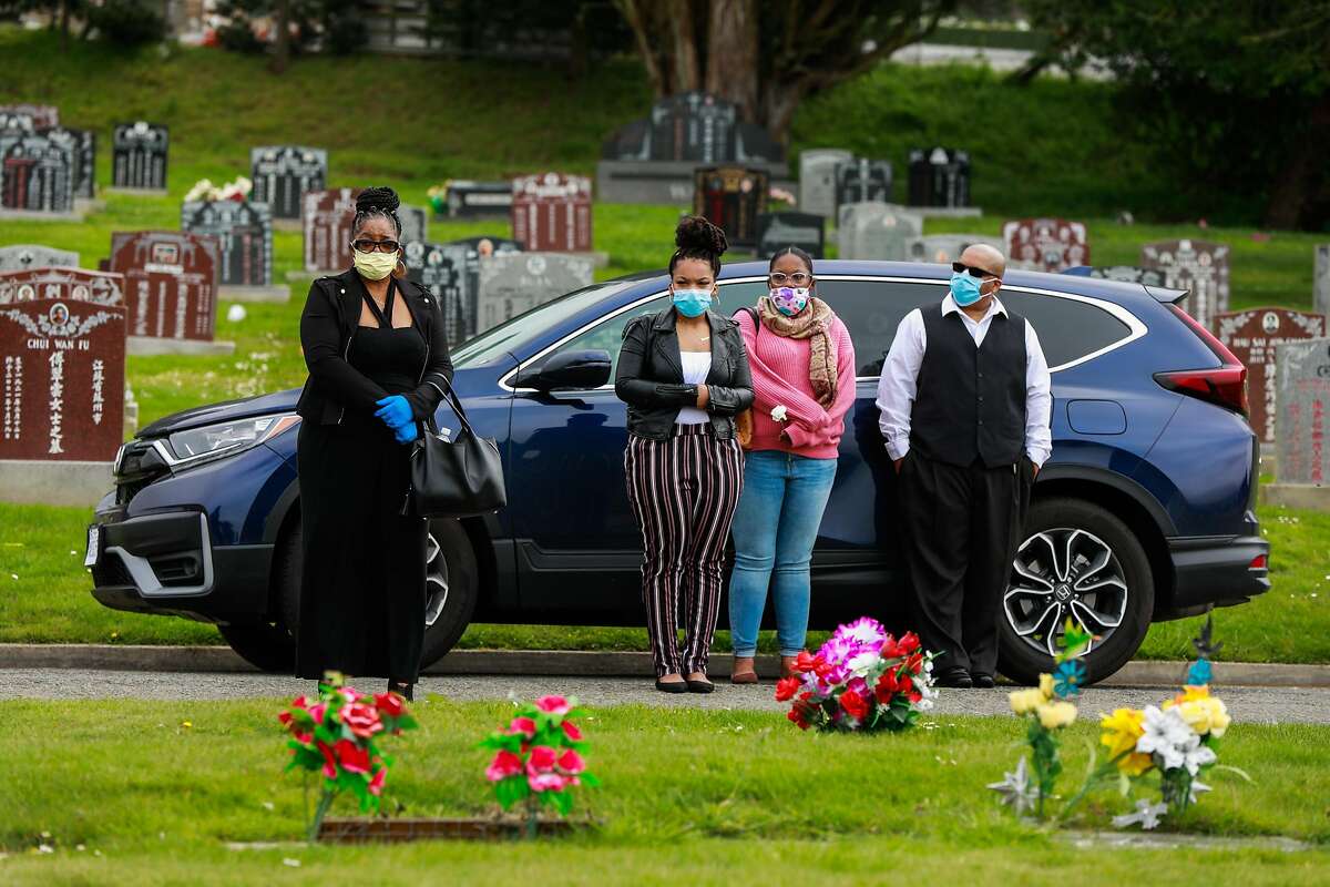 (L-r) Debra Holloway, Rashawn Henry, Raneisha Henry, and Robert Henry watch from the car as their mother and grandmother Tessie Henry who died of Covid-19 at the age of 83 is buried on Wednesday, April 8, 2020 in Colma, California.