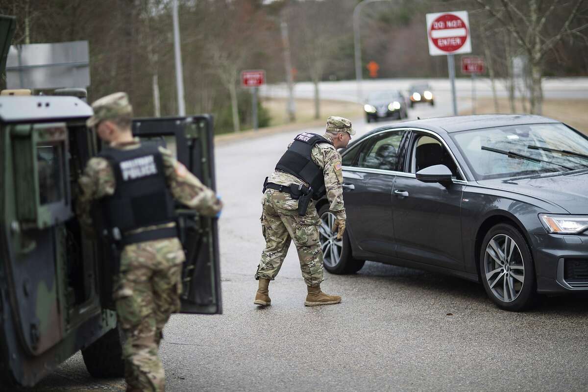 A member of the Rhode Island National Guard Military Police directs a motorist with New York license plates at a checkpoint on I-95 over the border with Connecticut where New Yorkers must pull over and provide contact information and are told to self-quarantine for two weeks, Saturday, March 28, 2020, in Hope Valley, R.I. Rhode Island Gov. Gina Raimondo on Saturday ordered anyone visiting the state to self-quarantine for 14 days and restricted residents to stay at home and nonessential retail businesses to close Monday until April 13 to help stop the spread of the coronavirus. (AP Photo/David Goldman)
