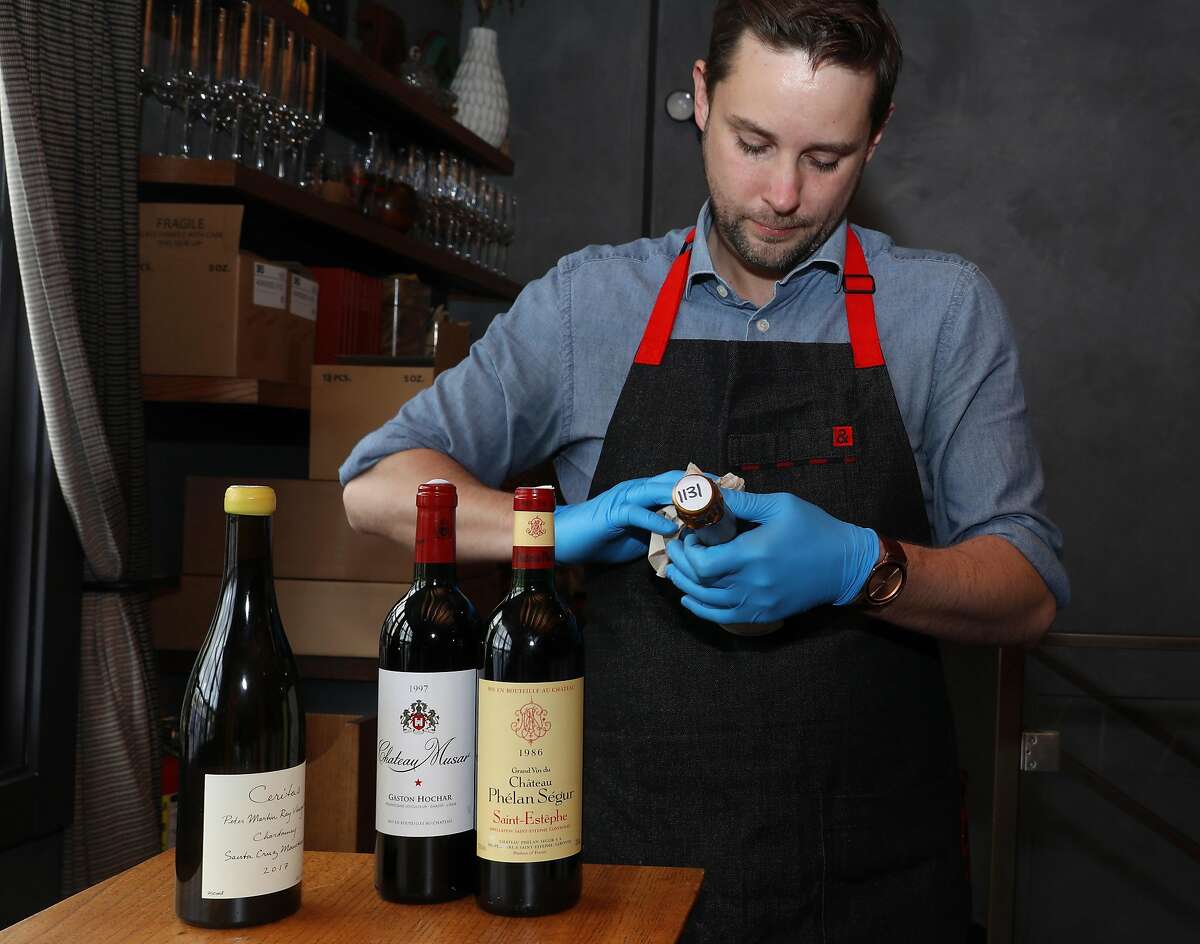 Beverage director Matt Dulle checks bottles of wine at Lazy Bear restaurant on Thursday, April 9, 2020, in San Francisco, Calif. Lazy Bear restaurant in the Mission has reconfigured its restaurant to be a "commissary," kind of like a general store, where customers can come shop for provisions and pick up bottles of wine, including some rare wines from Lazy Bear's cellar.