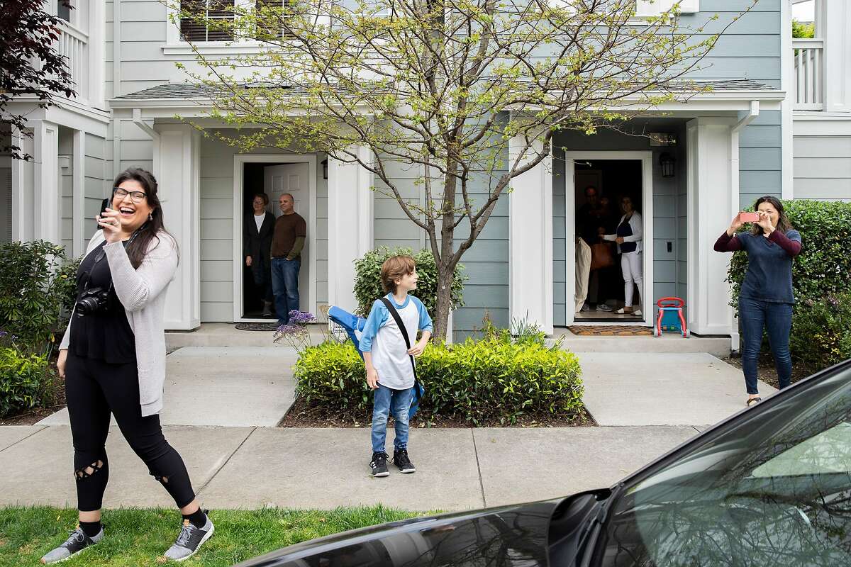 Christina Medeiros (left) and her son Stefano Medeiros, 7, (center) with neighbors watch a parade by fire and police department officials on Saturday, April 11, 2020, in Richmond, Calif. Christina�s son Nico Medeiros was surprised for his 9th birthday with a parade of three fire trucks and a police cruiser with their sirens on driving around the block for two times. The parade was arranged by Nico Medeiros� grandmother who couldn�t make it to Richmond from Florida. (This caption has been updated to correct the spelling of Nico's name)