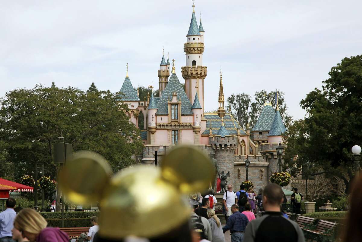 FILE - In this file photo, visitors walk toward Sleeping Beauty's Castle in the background at Disneyland Resort in Anaheim.