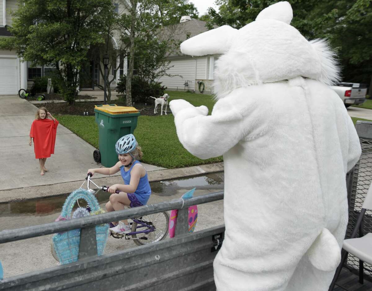 A family passes by as Michael Bisbee, dressed as the Easter Bunny, and his family drive around neighborhoods to spread some Easter joy.