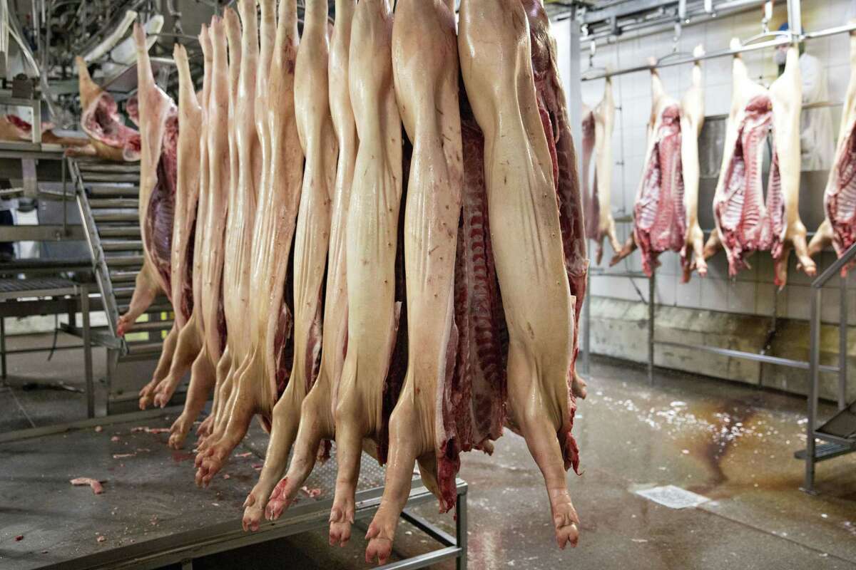 Pig carcasses hang from an overhead conveyor at a Smithfield Foods Inc. pork processing facility in Milan, Mo.