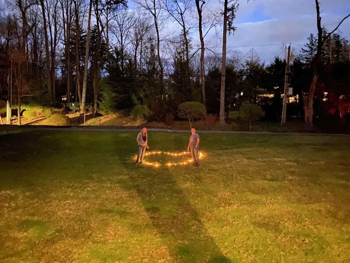 Greenwich residents Mary and Gary Dell’Abate stand by the lit candles left for them by their neighbors. Mary’s father died earlier in the month and family friends left the lit candles in a heart on their lawn as a show of love an support for her at a time when social distancing has made traditional comforting impossible. - Contributed photo