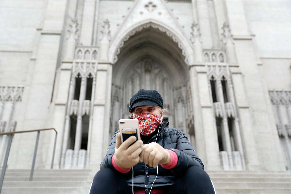 4月，旧金山，教区居民Jude Lange在格雷斯大教堂的台阶上观看虚拟的复活节礼拜。尽管最高法院决定允许在加州进行室内礼拜，但教堂将继续关闭。