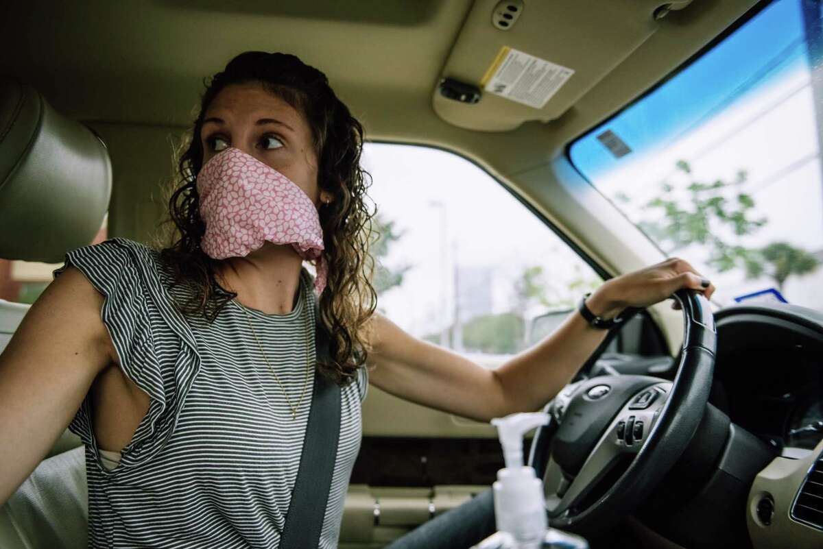 Postmates driver Rebecca Drexel wears a cloth mask, as recommended by the CDC, while she delivers food to customers in Houston. Drexel also keeps a bottle of hand sanitizer in her car, which she uses before and after every delivery.