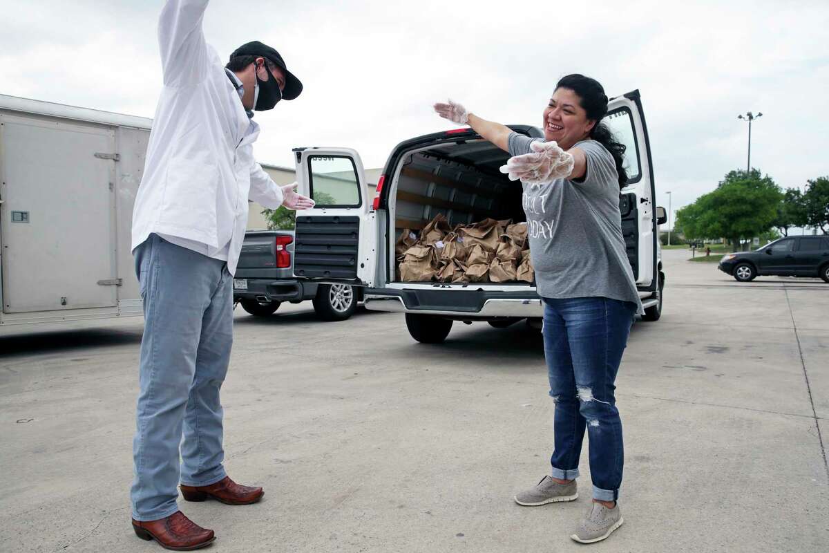 Luciano Ciorciari gets a "corona hug" from Elizabeth Lutz of the Health Collaborative as he rallies his employees at his Food Related headquarters in Schertz to assemble 400 Drop Off food deliveries on April 10, 2020.