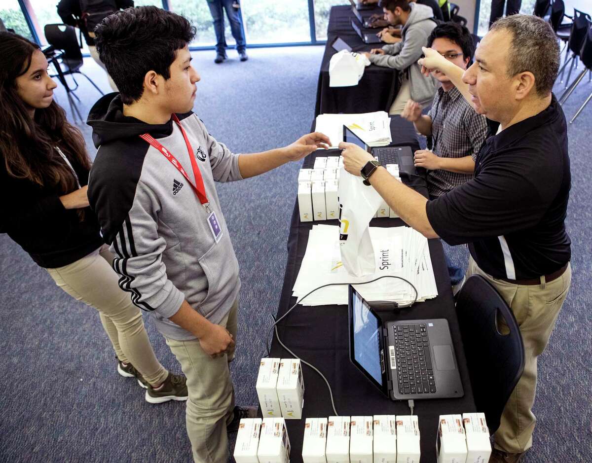 In this 2018 file photo, Jesse Martinez, left, receives his wireless internet hotspot device provided by the 1Million Project Foundation from Sam Houston Math, Science & Technology Center technology teacher Jose Ayala at the Houston ISD campus. About 21,500 district students already have a hotspot through the foundation, but more devices are needed amid the shutdown of schools due to the novel coronavirus, HISD officials said.