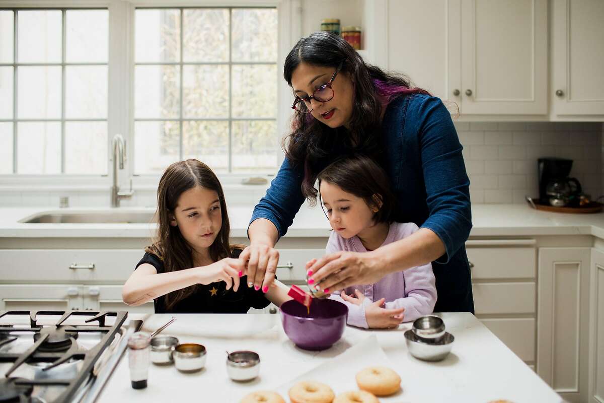 2020年3月5日，加利福尼亚州奥克兰，作家莉娜·特里维迪-格雷尼尔和她的女儿雷米和艾拉在厨房里制作芒果豆蔻甜甜圈。