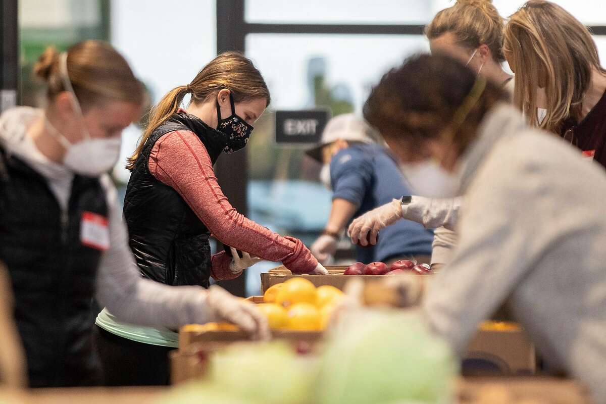 A volunteer wears a face mask and gloves while sorting fruit at the San Francisco-Marin Food Bank in San Rafael, Calif. Saturday, April 11, 2020. San Francisco-Marin Food Bank has set up several new distribution centers, including this drive-through one in San Rafael where residents pull up, pop their trunks and have the goods dropped in.