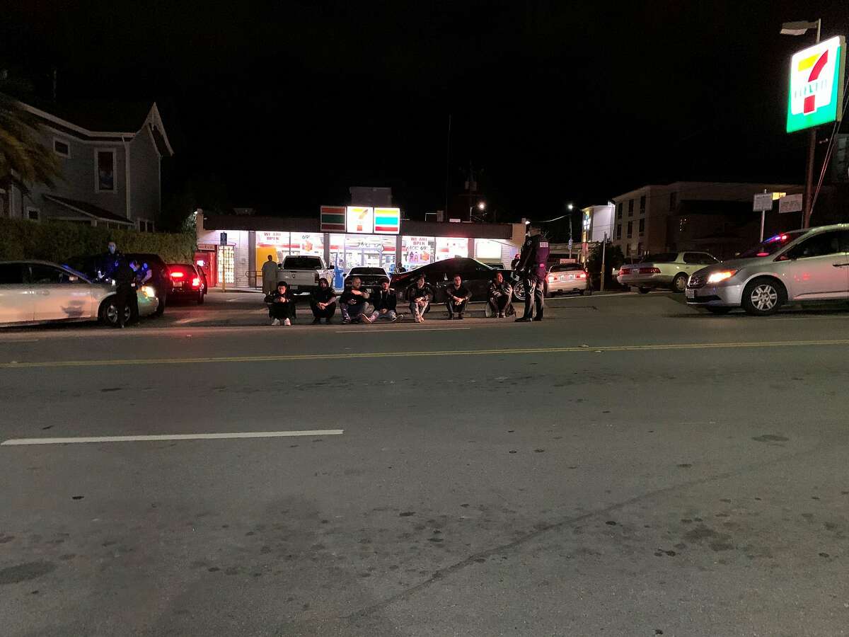 Seven Fremont residents sit on the curb outside 7-Eleven on Ocean Street in Santa Cruz after police fined them each $1,000 for violating county shelter-in-place orders meant to curb COVID-19 transmission.