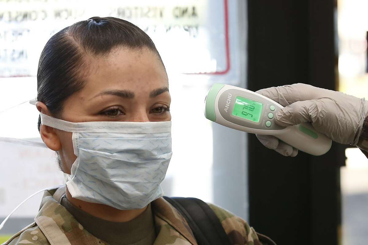 In this photo taken Friday April 10, 2020, Sgt. Alejandra Cabos has her temperature taken before entering the California National Guard Headquarters in Sacramento, Calif. Officials are recommending that evacuation shelters follow many of the procedures being used at the National Guard Headquarters if they must be activated during the coronavirus outbreak. Those entering wear face masks, have their temperatures taken and answer various health questions. (AP Photo/Rich Pedroncelli)