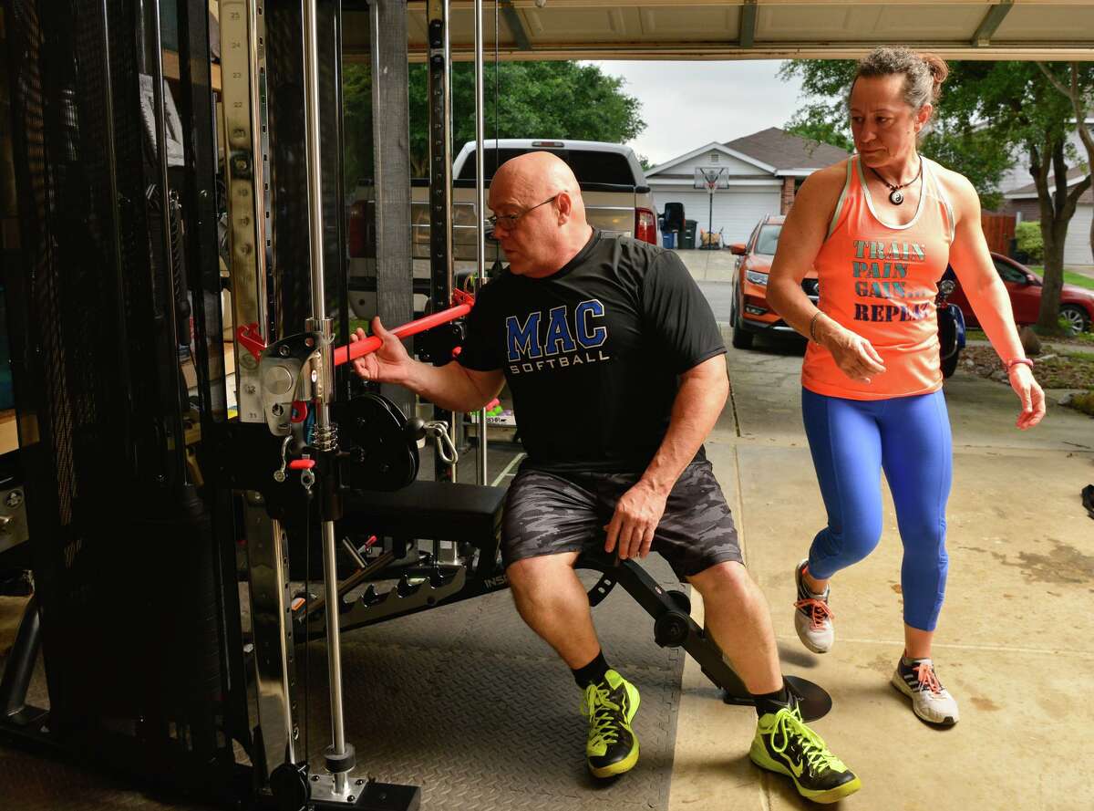 Kevin and Cristina Coble work out in their New Braunfels garage. The Cobles aren’t alone in bringing the gym to their home because their usual workout place has closed for the duration.