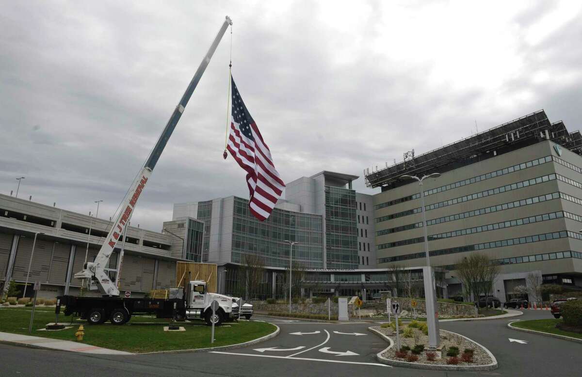Kyle DeLucia, Owner of K&J Tree Service, and his crew set up a crane at the entrance to Danbury Hospital with a 50 foot American flag and a giant Thank You sign to show their appreciation to the hospital staff serving the community during the covid pandemic. Tuesday, April 14, 2020, in Danbury, Conn.