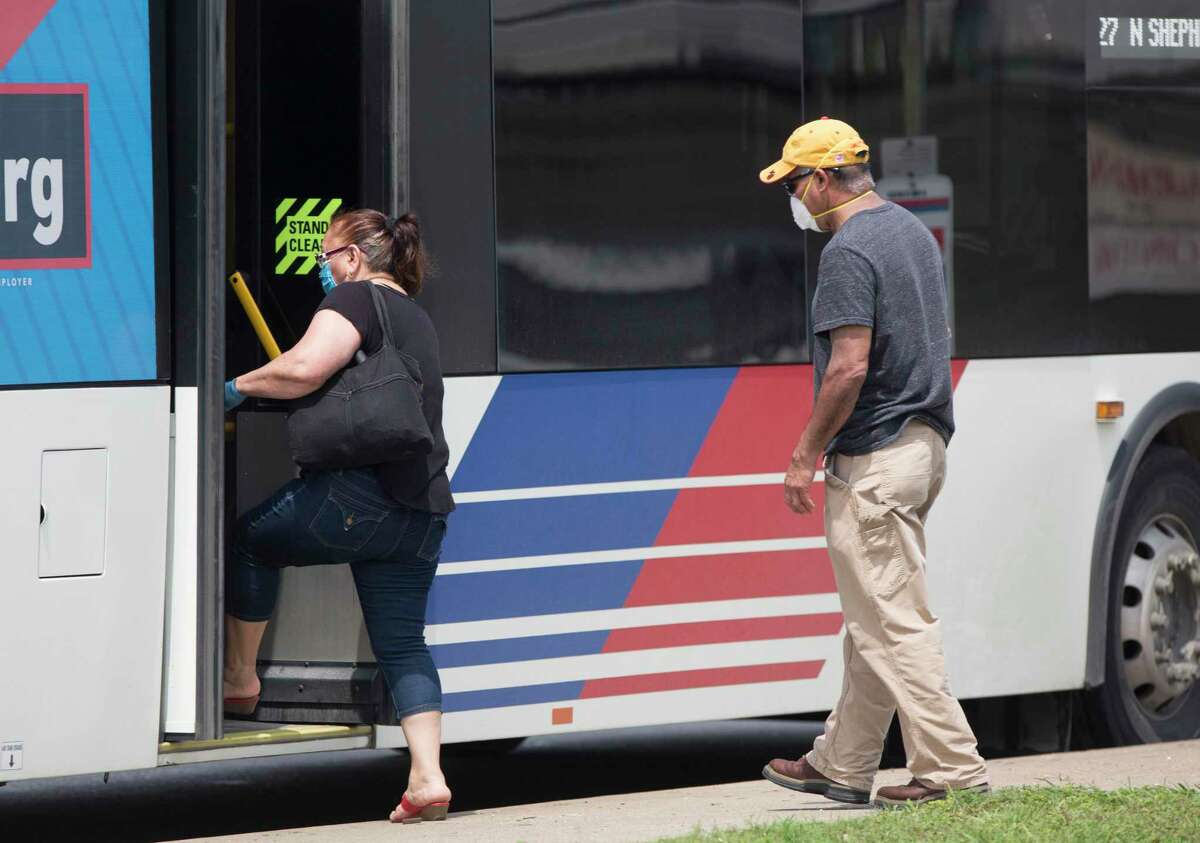 People wait for a Metropolitan Transit Authority Route 27 bus in masks and gloves on North Shepherd Drive on April 7, 2020, in Garden Oaks in Houston.