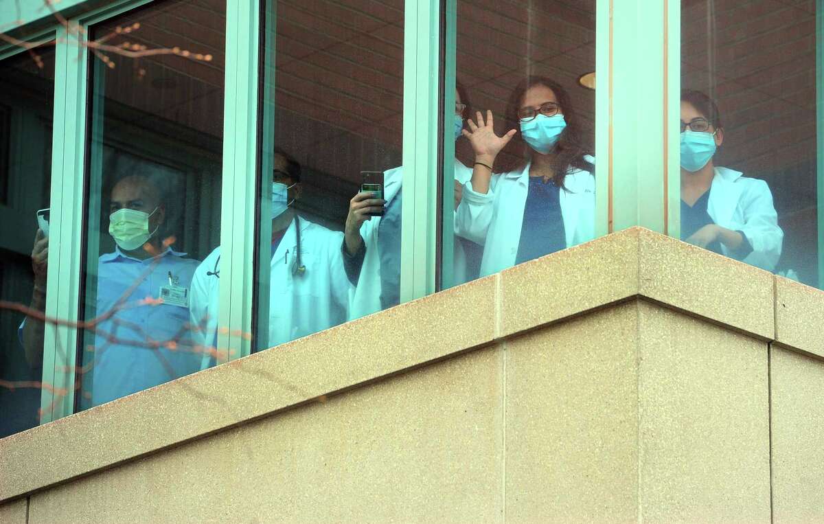 Griffin Hospital health care workers watch as dozens of fire, police, and EMS vehicles drive past as a thank you to their work in Derby, Conn., on Tuesday Apr. 14, 2020. Vehicles gathered at Nolan Field in Ansonia and rode in a parade along Wakelee Ave and then stopped briefly at the hospital to greet workers.