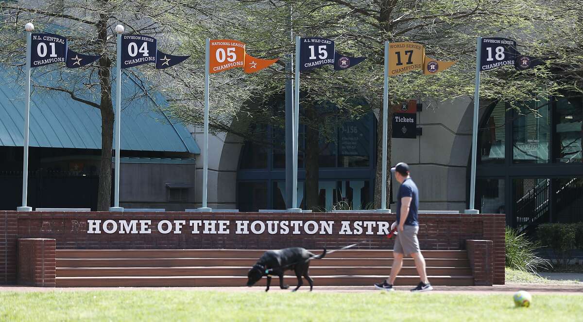 Brian Duhon walks his dog, Charlie, at the Plaza at Minute Maid Park in Houston, Wednesday, March 25, 2020, one day after Harris County Judge Lina Hidalgo issued a "stay at home, work safe" order.