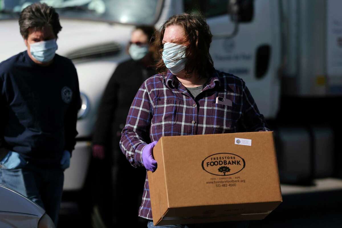 Volunteers and staff from St. Vincent de Paul and the Freestore Foodbank distribute more than 600 boxes of food, during the coronavirus pandemic, Wednesday, April 15, 2020, in Erlanger, Ky. (Kareem Elgazzar/The Cincinnati Enquirer via AP)