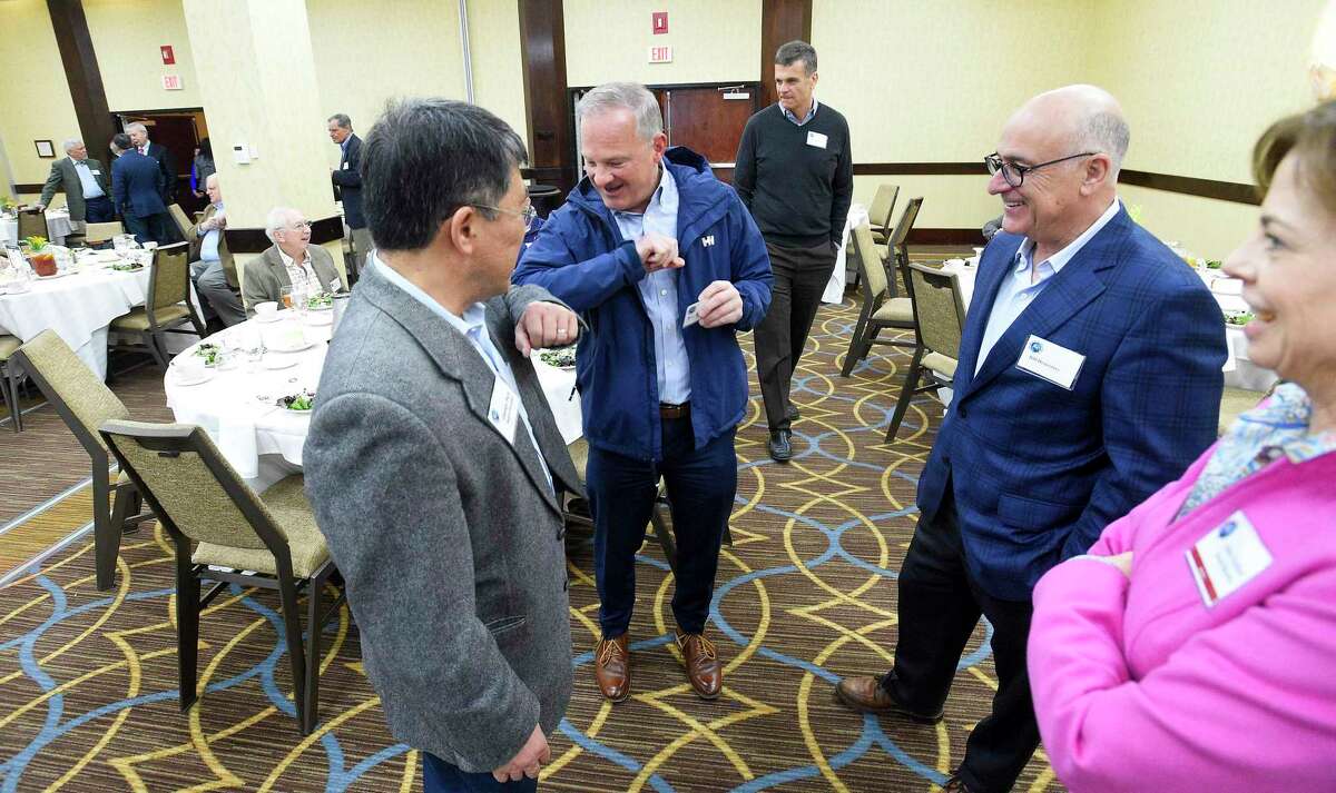 Attendees George Paik and Bill Catanzara elbow-bump each other as they prepare to listen to Dr. Sten Vermund of Yale School of Medicine discuss global warming and the coronavirus pandemic during a forum at the Stamford Sheraton hotel on March 11, 2020 in Stamford, Connecticut. The Stamford Sheraton announced April 13, 2020 that it was cutting about 100 positions amid the coronavirus crisis.