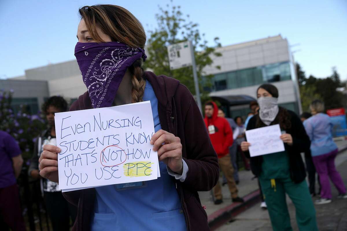 OAKLAND, CALIFORNIA - MARCH 26: Alameda Health System nurses, doctors and workers hold signs during a protest in front of Highland Hospital on March 26, 2020 in Oakland, California. Dozens of health care workers with Alameda Health System staged a protest to demand better working conditions and that proper personal protective equipment be provided in the effort to slow the spread of COVID-19. (Photo by Justin Sullivan/Getty Images)
