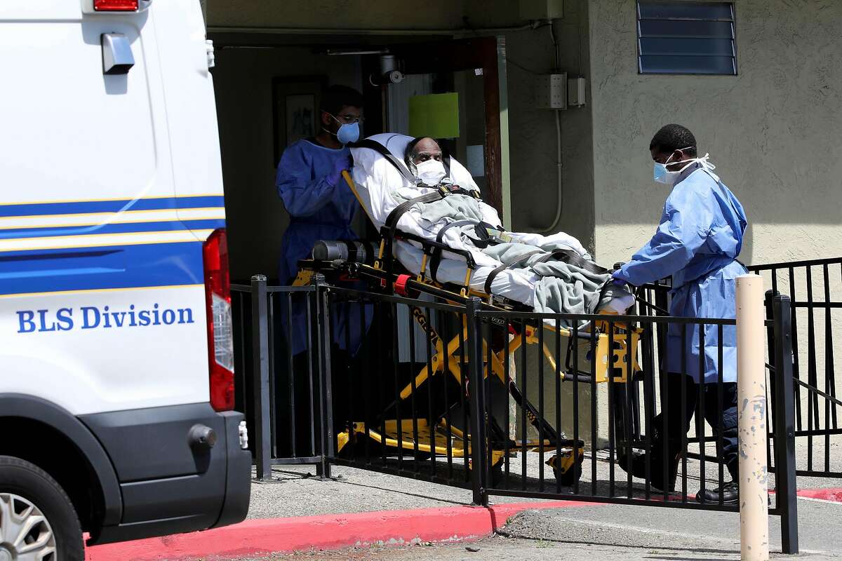 Employees with Falcon Critical Care Transport remove a patient from Gateway Care and Rehabilitation on Wednesday, April 15, 2020, in Hayward, Calif. The facility currently has eleven COVID-19 related deaths with dozens of staff members and patients infected with the novel coronavirus.