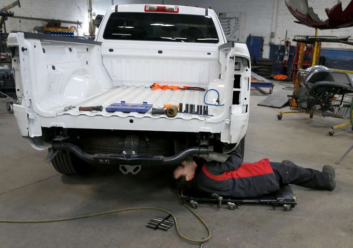 Thomas Lehman works under a pickup truck at George V. Arth and Son auto body shop in Oakland, Calif. on Wednesday, April 15, 2020. Fewer cars on the road during the coronavirus shelter-in-place orders has led to a large decline of business for car repair shops.