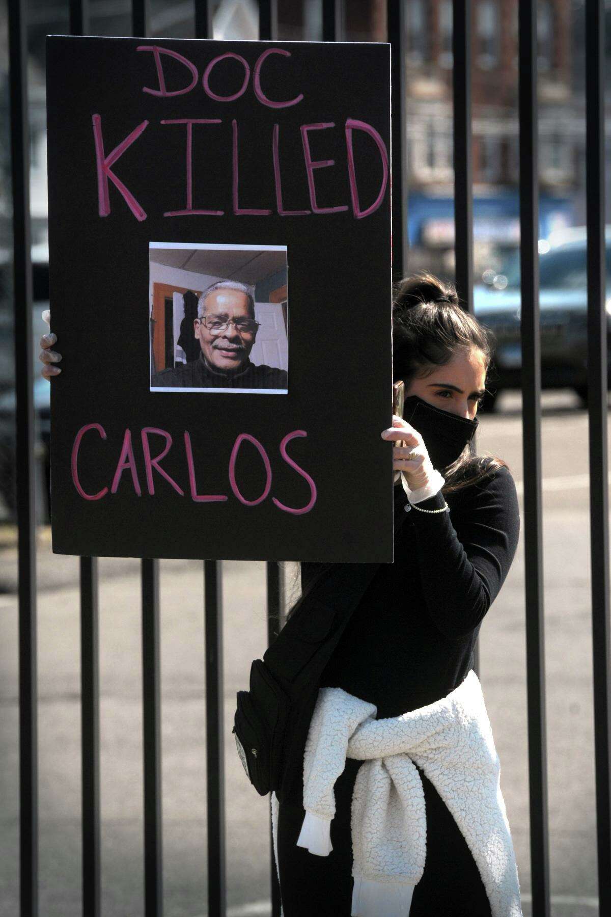 A woman holds a poster with the image of Carlos DeLeon during Wednesday’s protest. DeLeon died in a state prison Monday after contracting coronavirus.