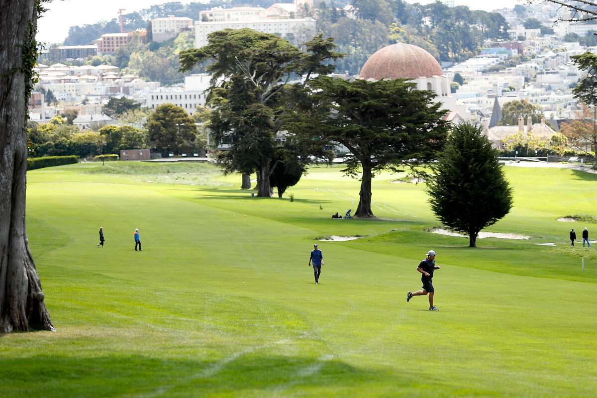 Joggers and walkers use a fairway at Presidio Golf Course in San Francisco, Calif., on Monday, March 30, 2020. The course is closed to golfers.