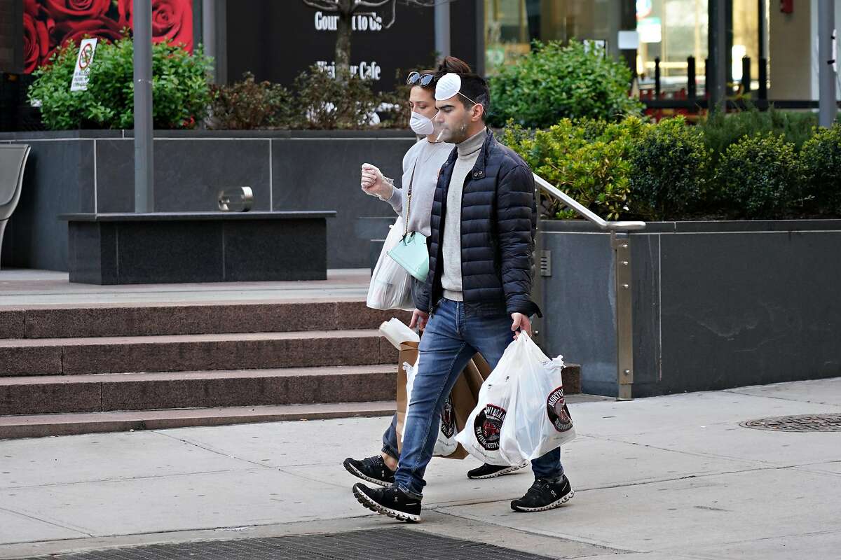 NEW YORK, NEW YORK - MARCH 26: People are seen wearing protective masks while smoking as the coronavirus continues to spread across the United States on March 26, 2020 in New York City. The World Health Organization declared coronavirus (COVID-19) a global pandemic on March 11th. (Photo by Cindy Ord/Getty Images)