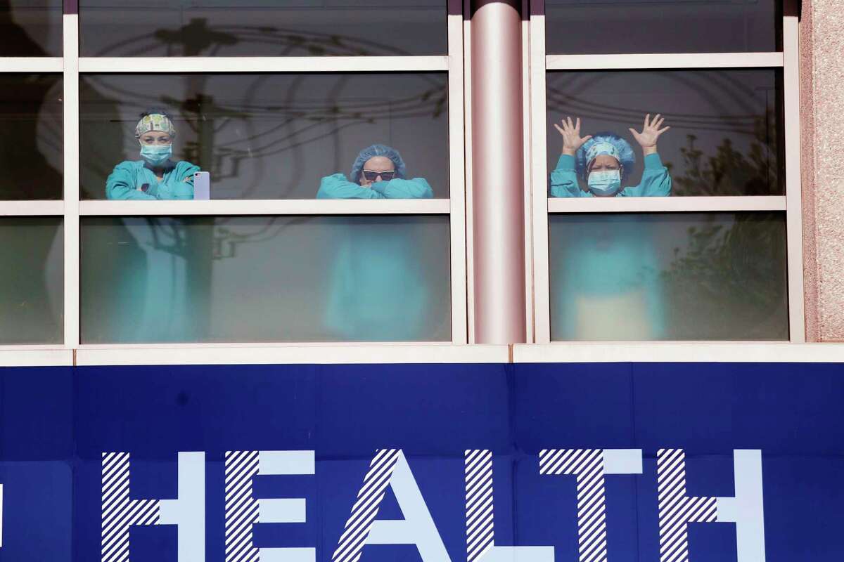 Swedish Medical Center health care workers battling the coronavirus outbreak look on from inside the hospital as first responders gathered outside in support of them Thursday, April 16, 2020, in Seattle. First responders across King County planned to stand outside of 15 hospitals in a show of appreciation for health care workers through the day Thursday.