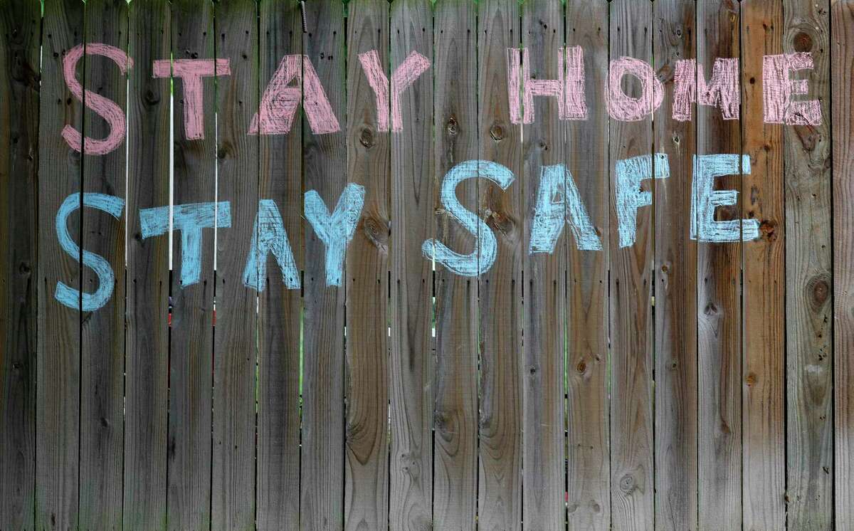 “Stay Home Stay Safe” is written in chalk on the fence in the Rivershire neighborhood, Tuesday, March 31, 2020, in Conroe.