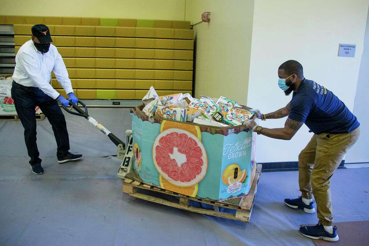 Harris County Commissioner Rodney Ellis, left, and Lawrence Battle roll a pallet of dry goods into the gym at the Julia C. Hester House recreation center on Thursday, April 16, 2020 in Houston. The county is teaming with the Houston Food Bank to provide food to residents impacted by coronavirus. The initiative will allow the food bank to give hundreds of thousands of pounds of food to people who are in need during the pandemic.