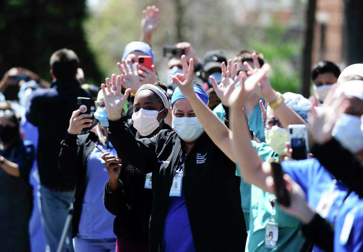 Hospital workers wave and cheer outside Greenwich Hospital as first responders pass by in a caravan of lights and sirens in Greenwich, Connecticut on April 16, 2020. The first responders arrived in police vehicles, EMS ambulances, and fire department trucks to give thanks to healthcare workers for their efforts in combating the coronavirus (COVID-19) pandemic.