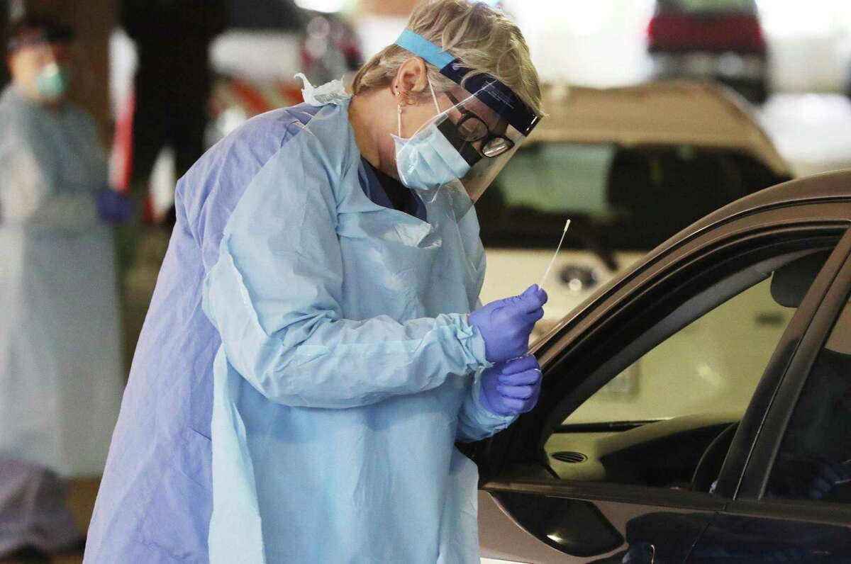 A nurse collects a nasal swab sample from a University of Washington Medicine employee in their car in Seattle.