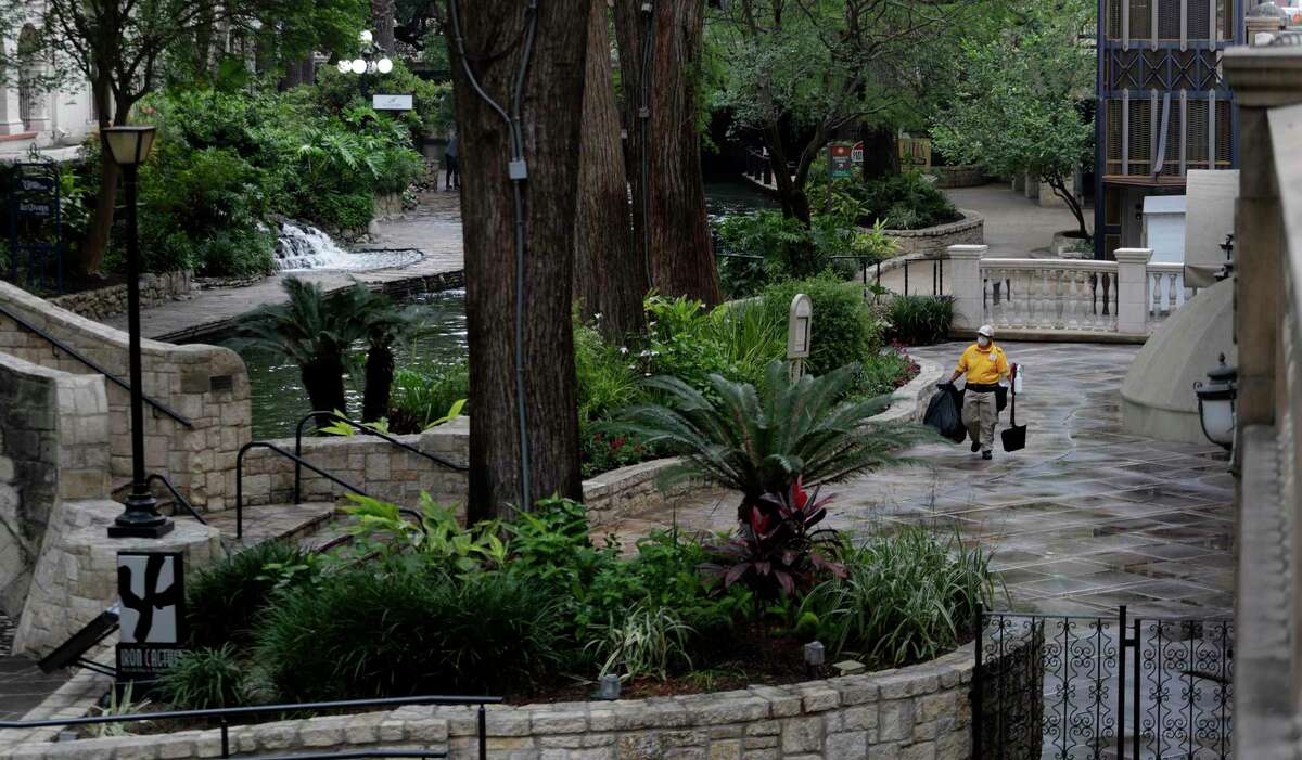 A worker wipes down handrails and other surfaces along the mostly empty River Walk in San Antonio, Monday, March 30, 2020. Due to the COVID-19 outbreak, San Antonio an many other Texas cities are under stay at home orders. (AP Photo/Eric Gay)