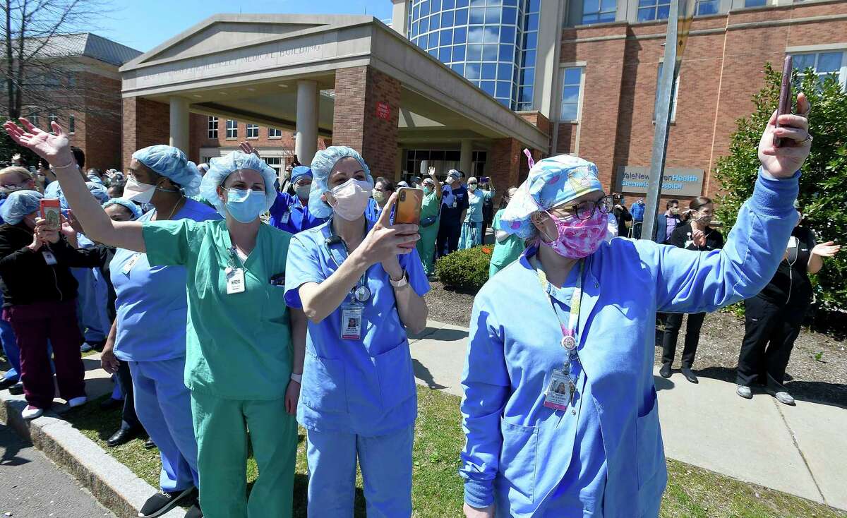 From left, Nurses from Labor and Delivery, Jessica Wieneke, Melissa Muller and Annie Gallagher, along with othe hospital workers wave and cheer outside Greenwich Hospital as first responders pass by in a caravan of lights and sirens in Greenwich, Connecticut on April 16, 2020. The first responders arrived in police vehicles, EMS ambulances, and fire department trucks to give thanks to healthcare workers for their efforts in combating the coronavirus (COVID-19) pandemic.