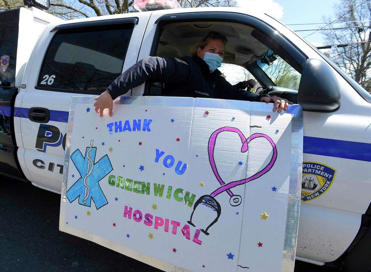 A Rye, New York police unit thanks hospital workers, as they wave and cheer outside Greenwich Hospital as first responders pass by in a caravan of lights and sirens in Greenwich, Connecticut on April 16, 2020. The first responders arrived in police vehicles, EMS ambulances, and fire department trucks to give thanks to healthcare workers for their efforts in combating the coronavirus (COVID-19) pandemic.