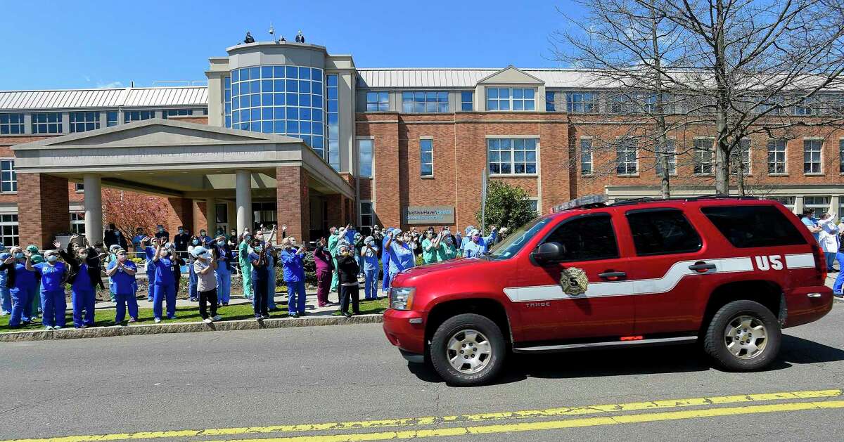 Hospital workers wave and cheer outside Greenwich Hospital as first responders pass by in a caravan of lights and sirens in Greenwich, Connecticut on April 16, 2020. The first responders arrived in police vehicles, EMS ambulances, and fire department trucks to give thanks to healthcare workers for their efforts in combating the coronavirus (COVID-19) pandemic.