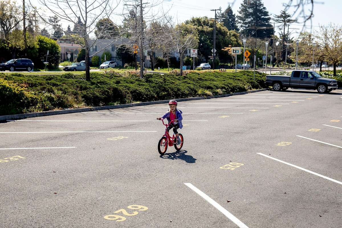 Jasmine Gleason, 7, rides her bike through an empty parking lot at North Berkeley BART Station in Berkeley, Calif. Tuesday, April 7, 2020. With schools and workplaces closed through the shelter-in-place order, parents are getting creative with entertaining their children through the day and public transit has seen a decline in ridership, leaving its parking lot open for bike riding and other recreation.