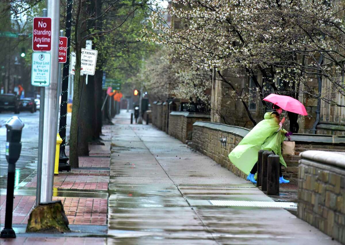A woman walks in the rain on an empty York Street in New Haven on Monday, April 13, 2020. Connecticut’s labor department reported that the state lost jobs in March 2020 and saw its unemployment jump to