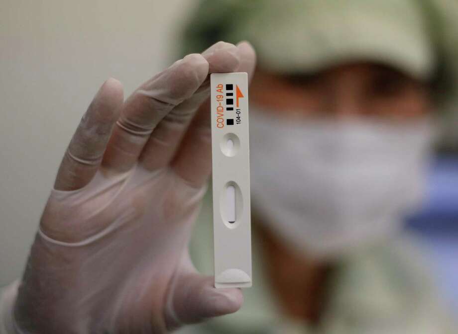 An employee holds up an antibody test cartridge of the ichroma COVID-19 Ab testing kit used in diagnosing the coronavirus for a photograph on a production line of the Boditech Med Inc. in Chuncheon, South Korea, Friday, April 17, 2020. Boditech Med recently started exporting its antibody-based virus test kits to various countries. Photo: Lee Jin-man, AP / Copyright 2020 The Associated Press. All rights reserved