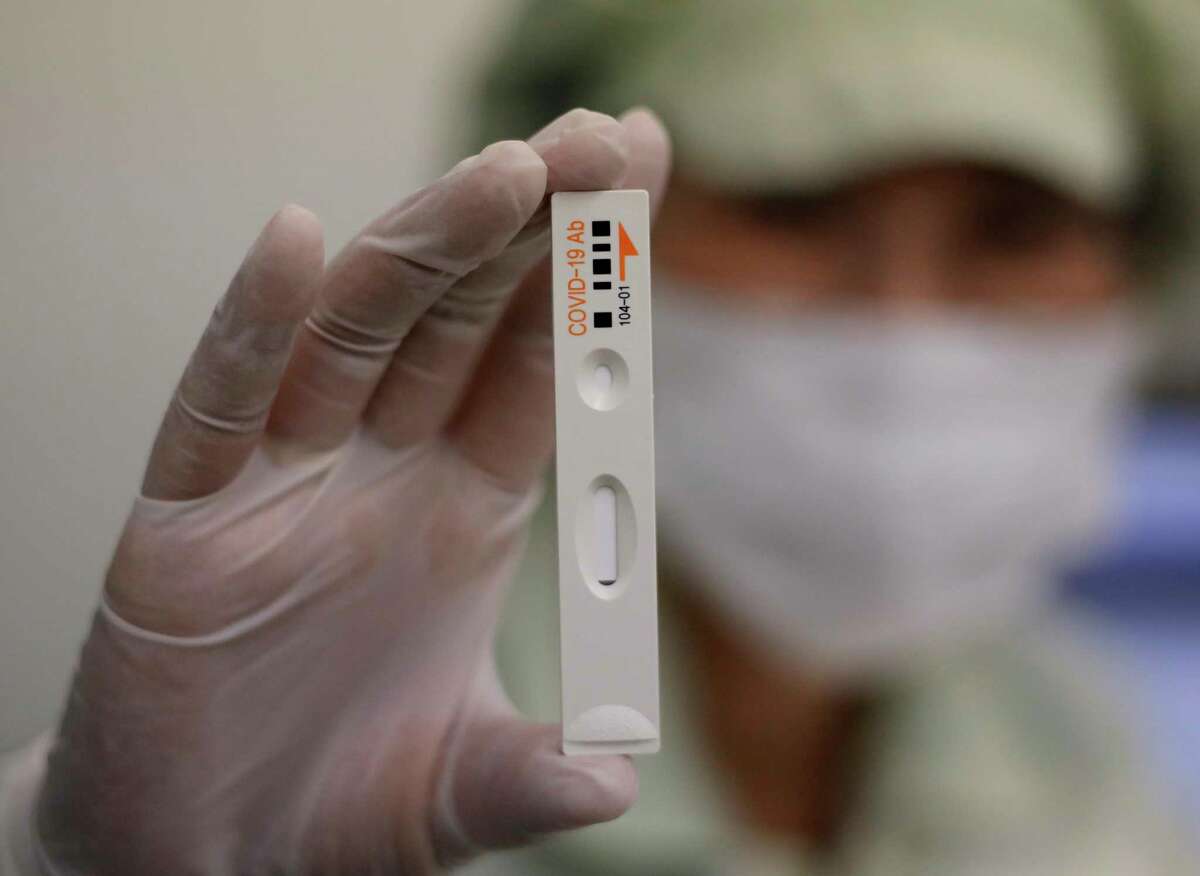 An employee holds up an antibody test cartridge of the ichroma COVID-19 Ab testing kit used in diagnosing the coronavirus for a photograph on a production line of the Boditech Med Inc. in Chuncheon, South Korea, Friday, April 17, 2020.