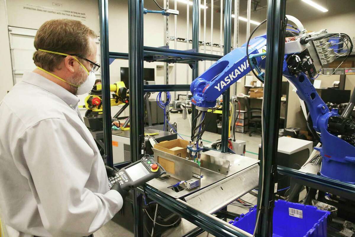 David Brain watches a machine move a box as Plus One Robotics employees work on tuning operations of warehouse robots on April 16, 2020.